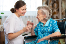 caregiver giving water to senior woman