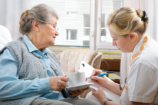 caregiver writing a note for medication to senior woman